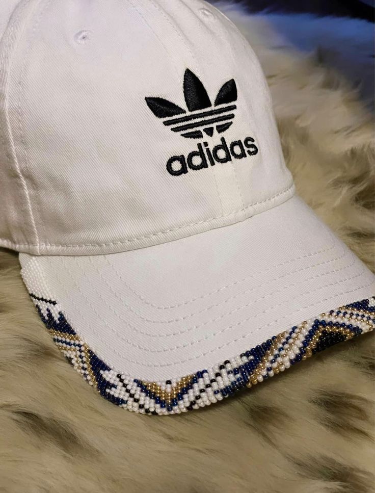 a white adidas hat sitting on top of a furry surface