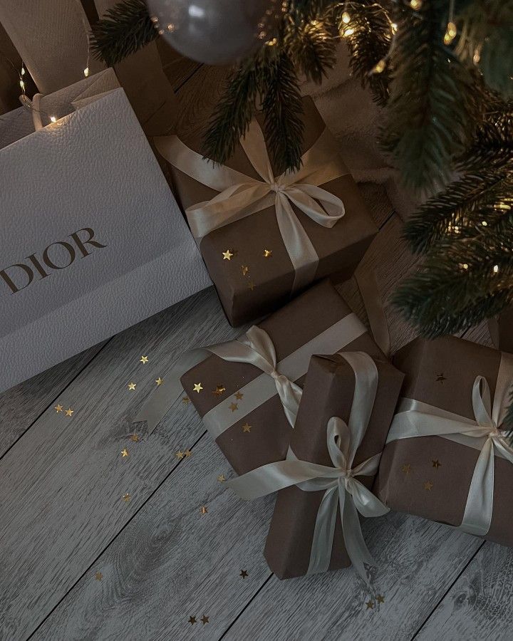 presents under the christmas tree are wrapped in brown paper with white ribbon and gold stars