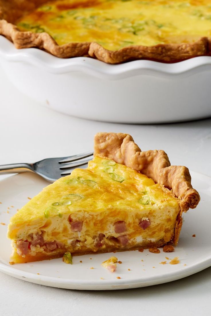 a slice of ham and cheese quiche on a plate next to a pie dish