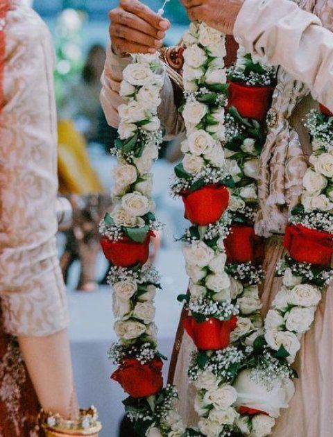 two people standing next to each other with flowers in their hands and one holding something