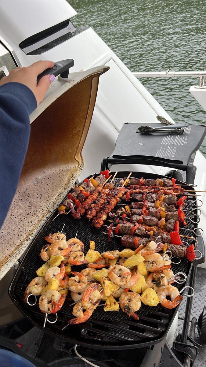 a person grilling shrimp and pineapple skewers on a boat