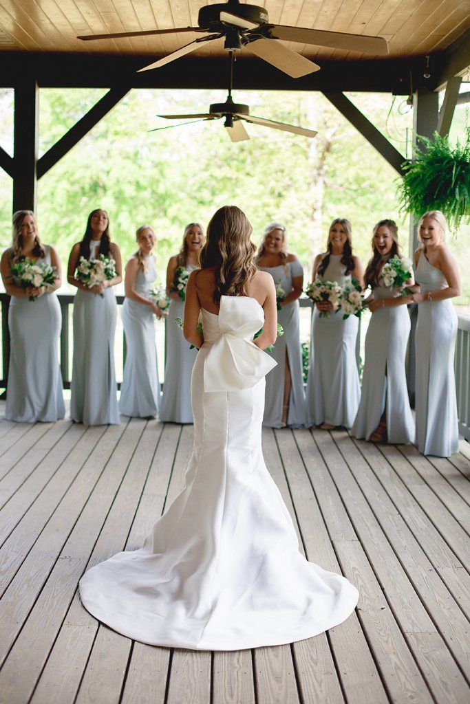 a bride and her bridal party standing on the deck with their bouquets in hand