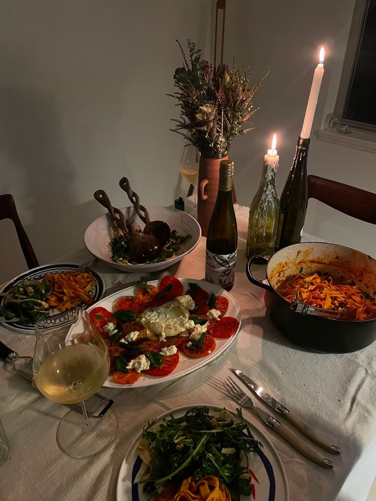 a table topped with plates of food next to candles and wine glasses on top of a table