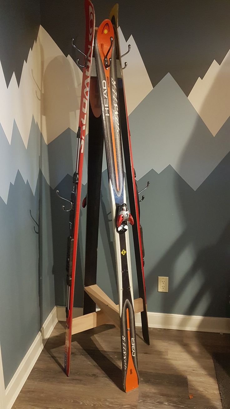 two skis are propped up on a stand in front of a wall with mountains painted on it