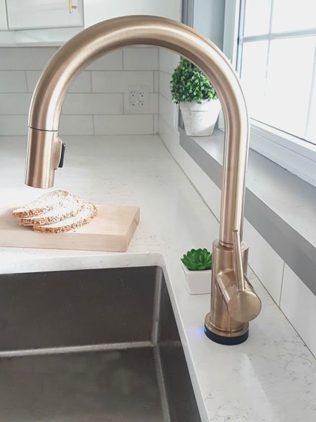 a kitchen sink with a wooden cutting board next to it and a window in the background