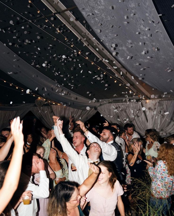 a group of people standing around each other in a room with confetti falling from the ceiling