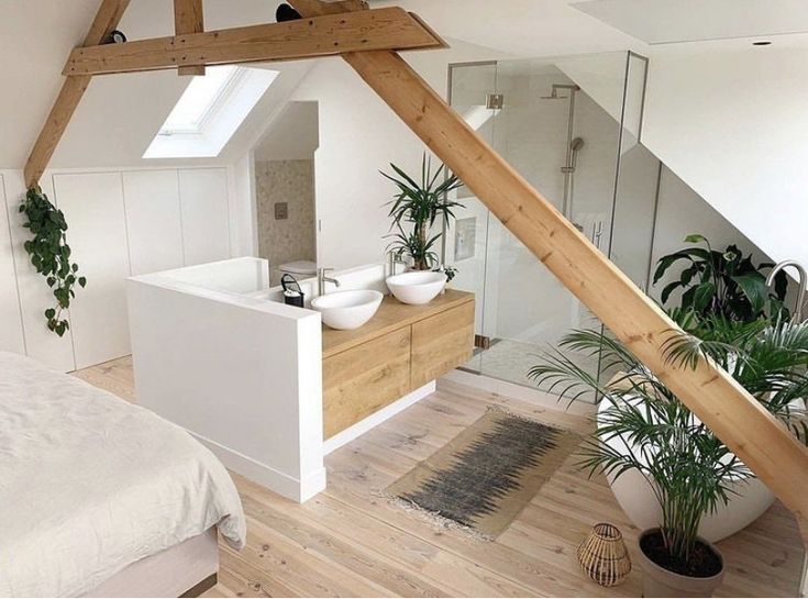 an attic bedroom with white walls and wood flooring is pictured in this image, there are potted plants on the bed