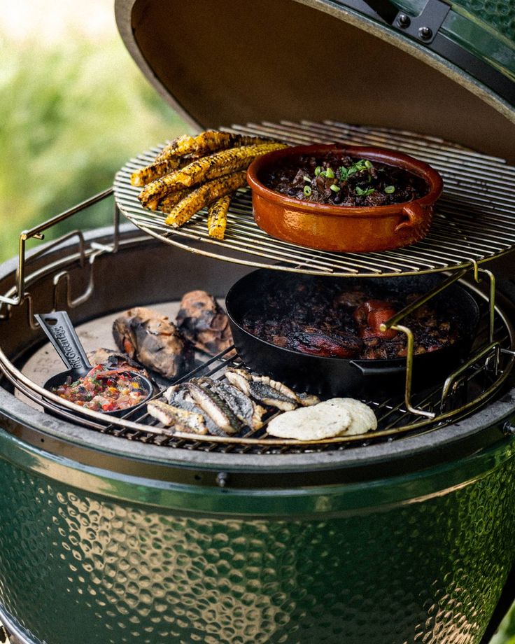 an outdoor grill with food cooking on it's sides and other foods being cooked