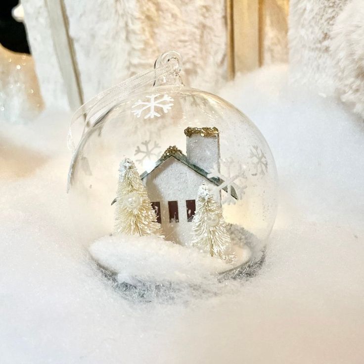 a glass ornament with a house in the snow on it's side