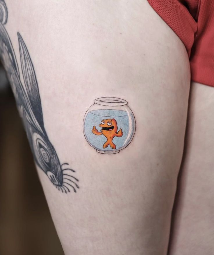 a woman's thigh with a fish in a bowl tattoo on her left side