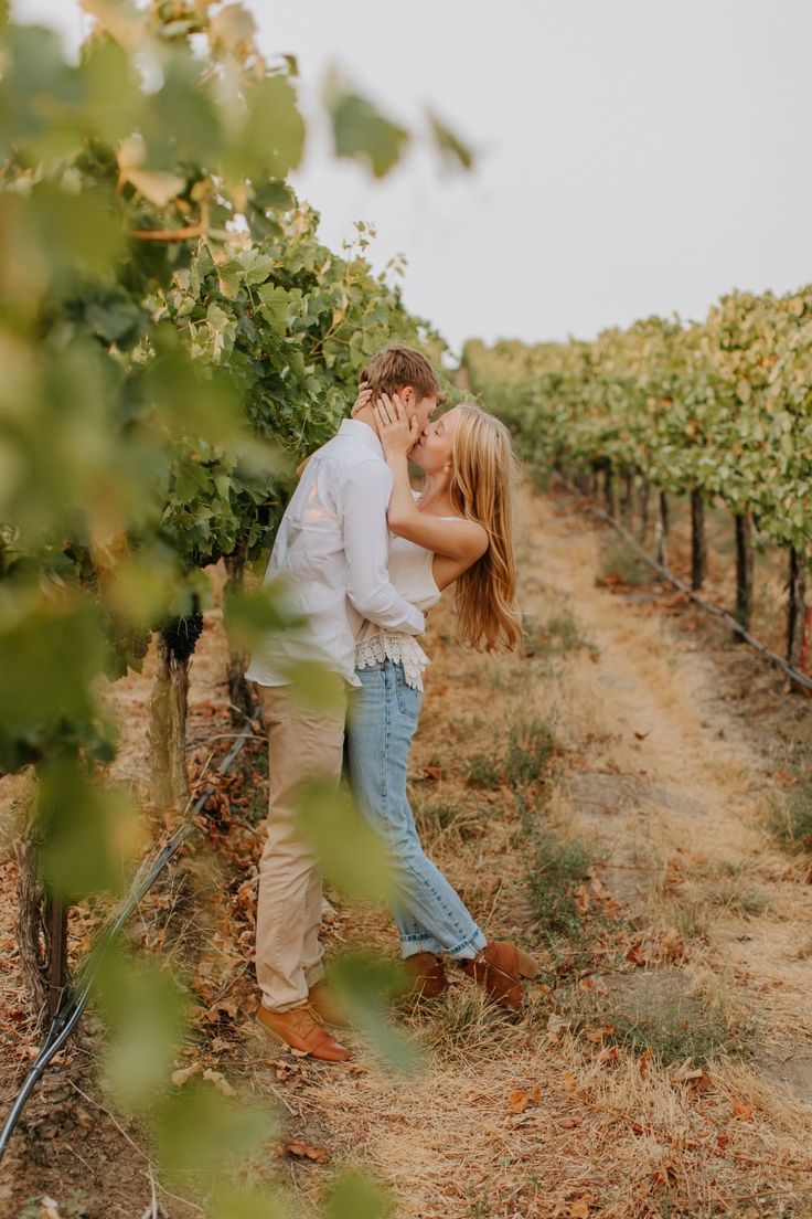 a man and woman kissing in the middle of a vineyard