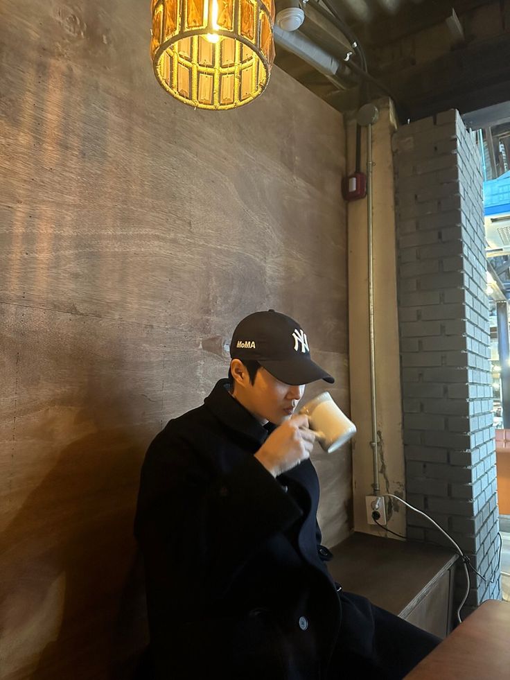 a man sitting at a table in front of a wall with a light hanging from it