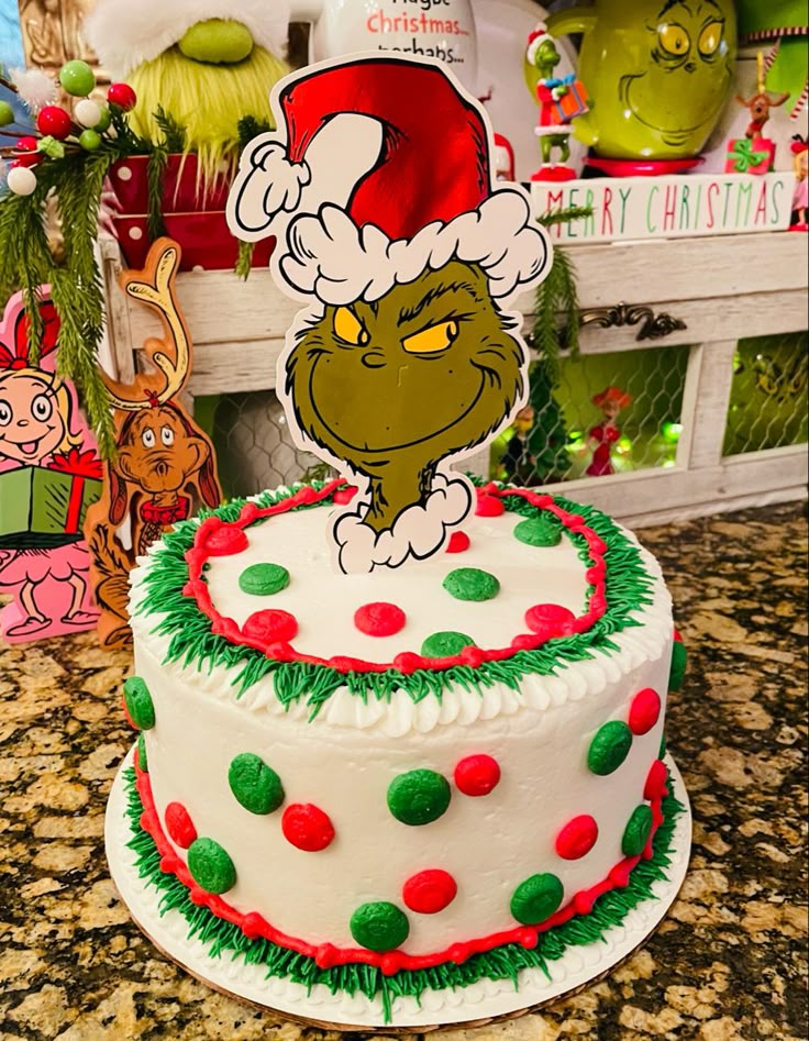 there is a christmas cake with the grin on it's top and decorations around it