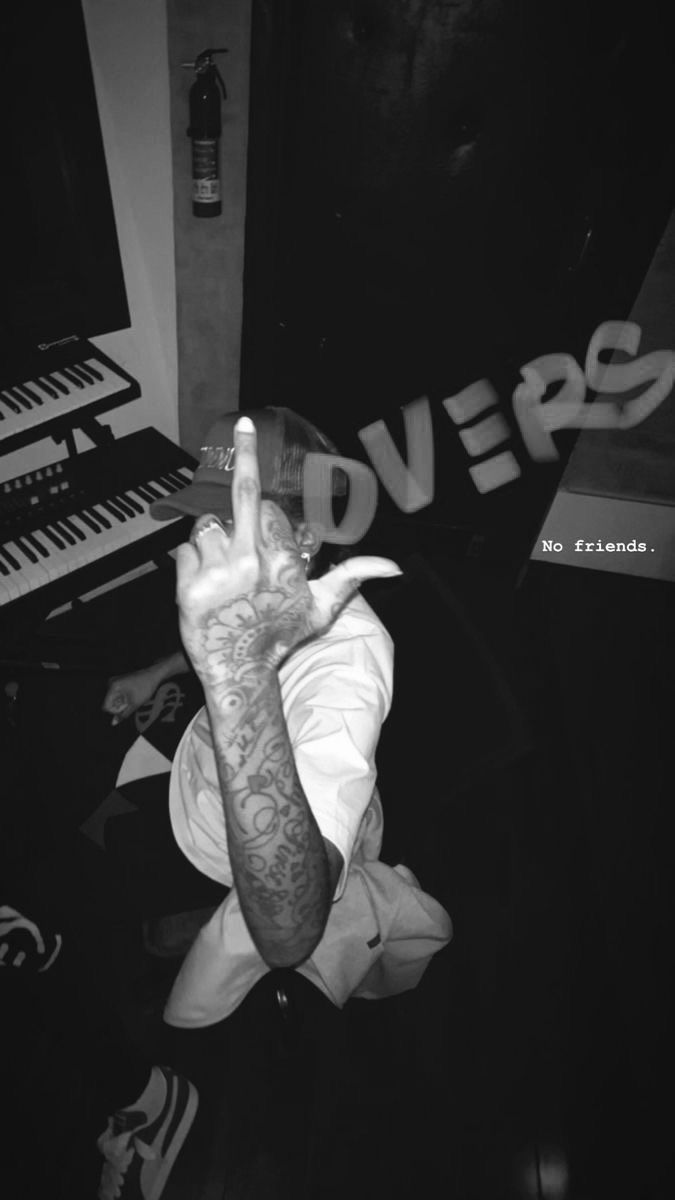 a man sitting in front of a keyboard making the peace sign with his hand and fingers