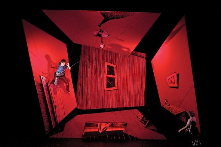 two children are climbing up the walls in a play room with red lighting and black curtains