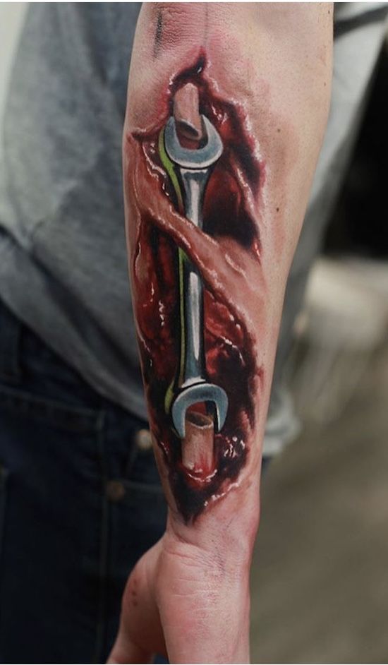 a man with a tattoo on his arm holding a wrench