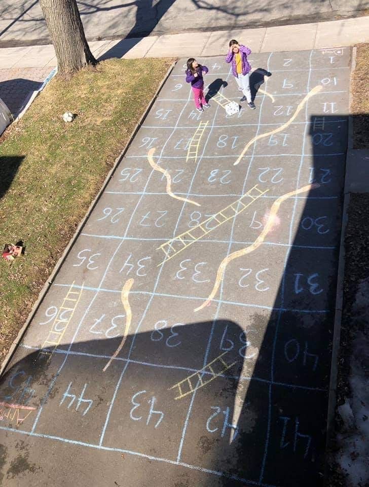 two people are standing on the sidewalk with chalk drawings in front of them and one person is holding an umbrella