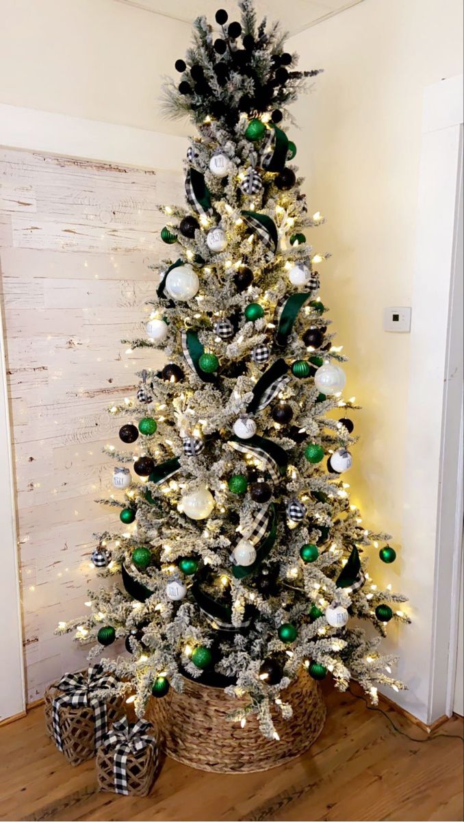 a white christmas tree with green and silver ornaments in a basket next to a wall