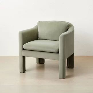 a green chair sitting on top of a hard wood floor next to a white wall