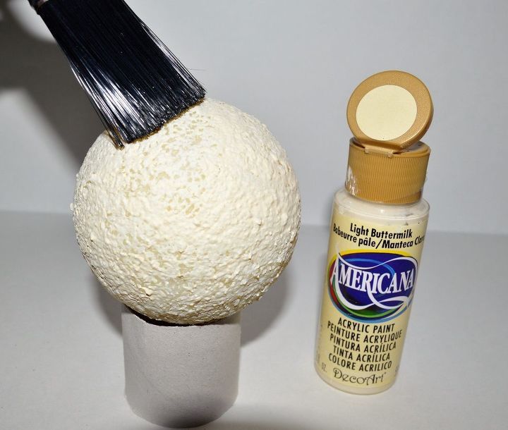 a paint brush is sitting next to a white ball and bottle of glue on a table