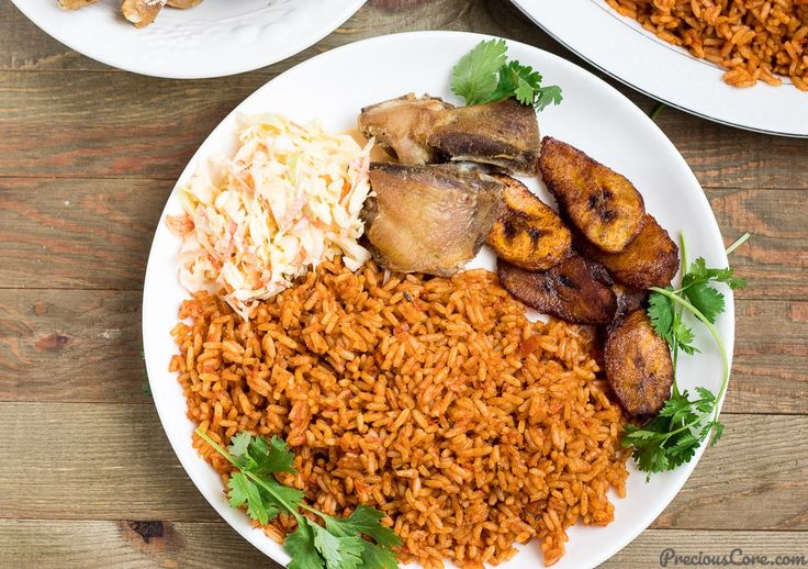 two plates filled with rice, meat and other food on top of a wooden table