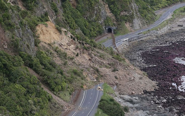 an aerial view of a road going into a tunnel on the side of a mountain