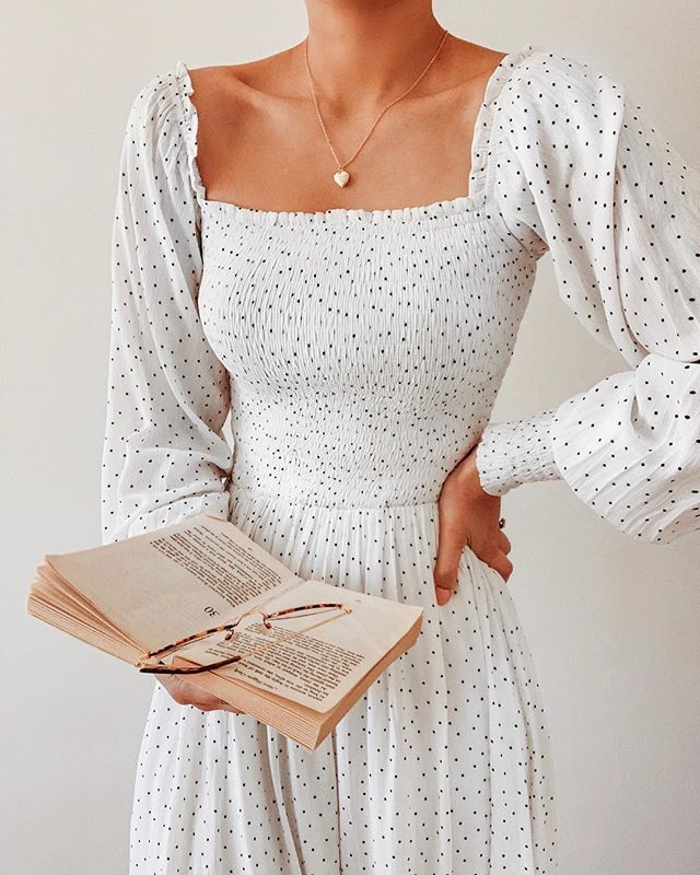 a woman in a white dress holding an open book