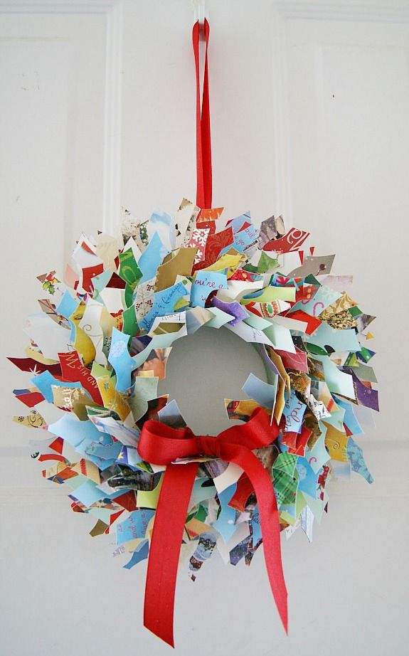 a wreath hanging from the front door decorated with colorful paper cranes and red ribbon tied around it