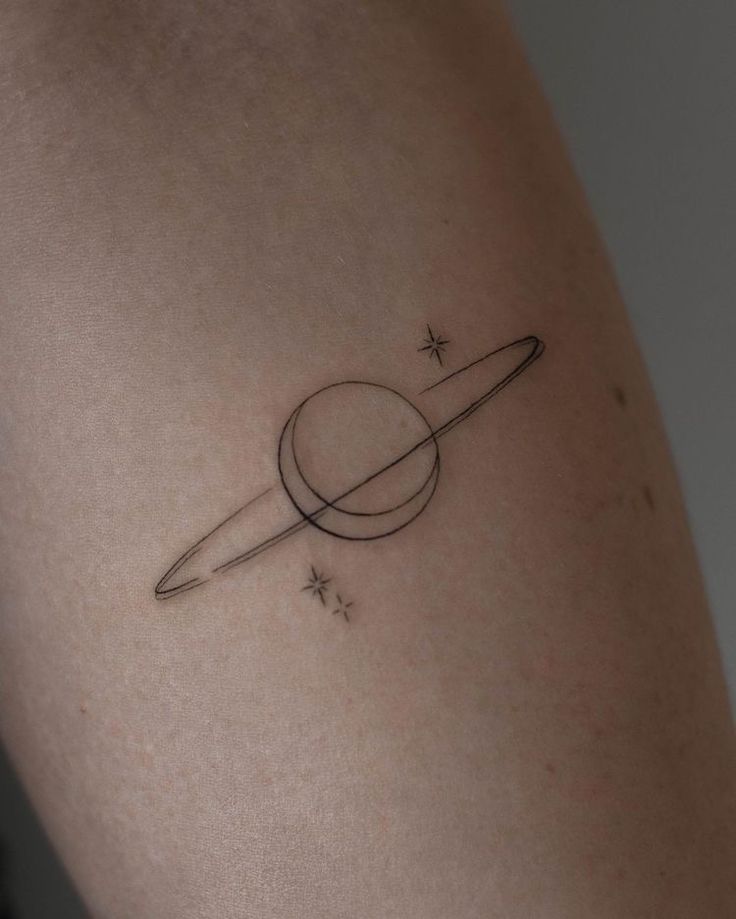 a small saturn tattoo on the back of a woman's right arm with stars around it