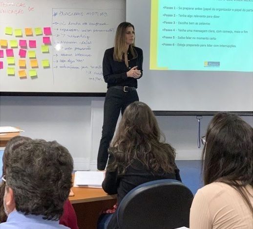 a woman standing in front of a class room full of people