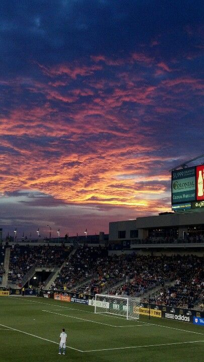 a soccer field with the sun setting in the background