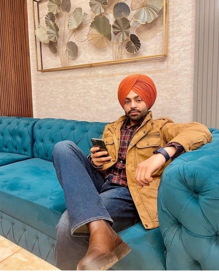 a man sitting on top of a blue couch holding a cell phone in his hand