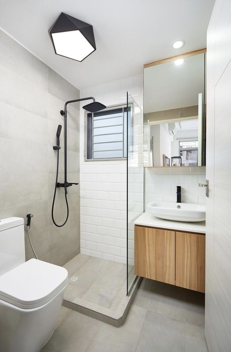 a bathroom with a toilet, sink and shower head mounted to the side of the wall