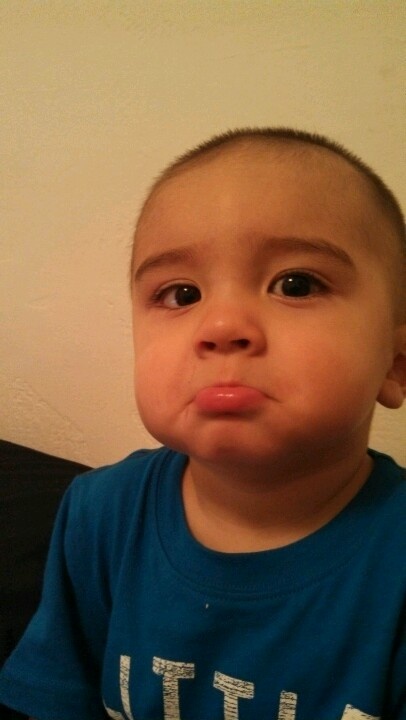 a young boy making a funny face while wearing a blue shirt