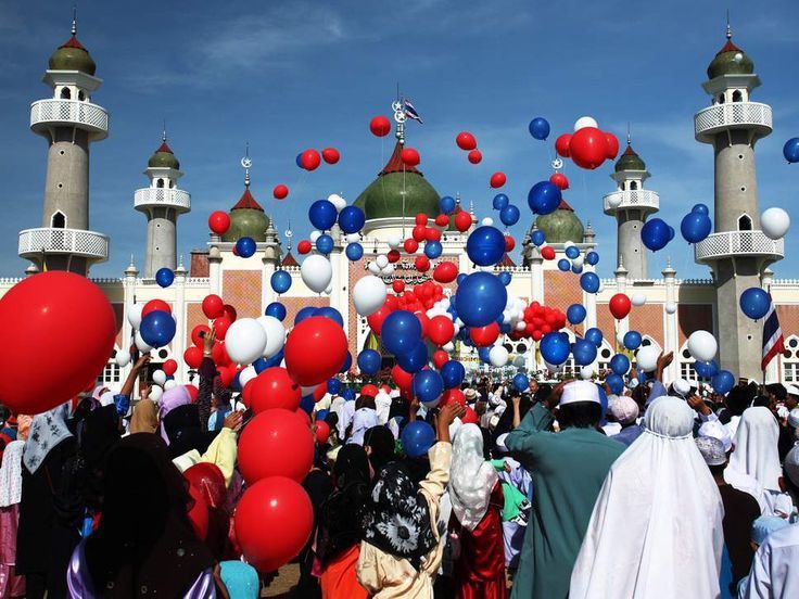 many people are standing in front of a building with red, white and blue balloons