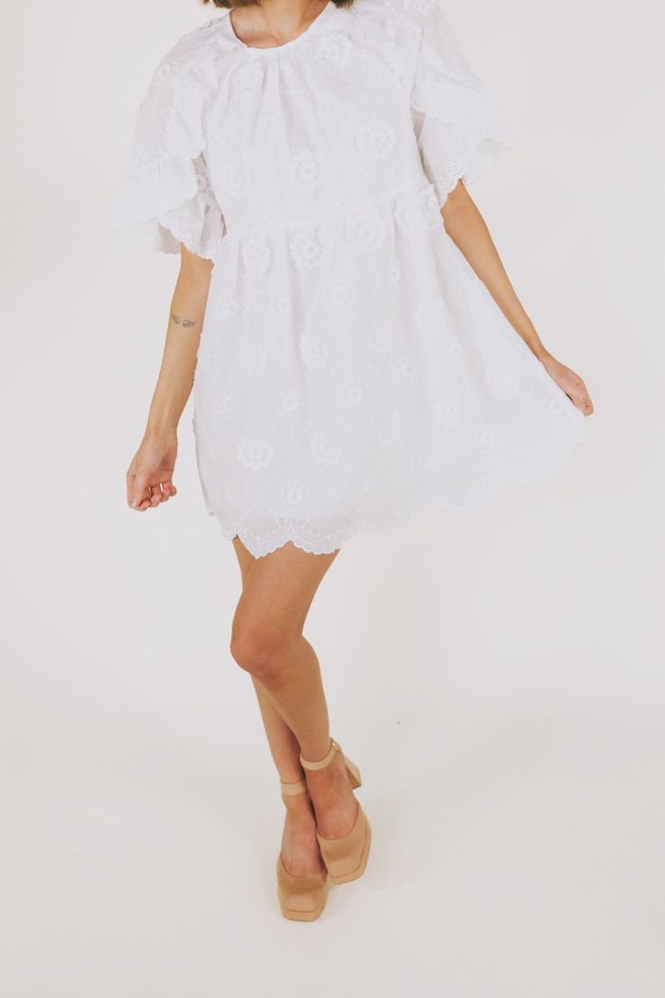 This white embroidered floral mini dress is the epitome of romantic elegance. Featuring a delicate scallop hemline and ruffle lace details, it is the perfect addition to any summer wardrobe. Enhance your feminine charm and steal hearts wherever you go with this beautiful dress. Details Round neckline Keyhole closure Ruffle lace details Embroidered fabricaiton Scallop hemline Lined Pockets Sizing Approximate measurements: SIZE LENGTH BUST WAIST Small 33” 36” 36” Medium 33” 38” 38” Large 34” 40” 4 Summer Brunch Dresses With Scalloped Edges, Flowy Lace Dresses With Floral Embroidery, Summer Flowy Scalloped Lace Dress, Flowy Scalloped Lace Dress For Summer, Flowy Scalloped Lace Summer Dress, Feminine Floral Embroidered Mini Dress For Summer, White Summer Dress With Scalloped Edges, White Summer Dresses With Scalloped Edges, Feminine Ruffled Lace Dress For Garden Party