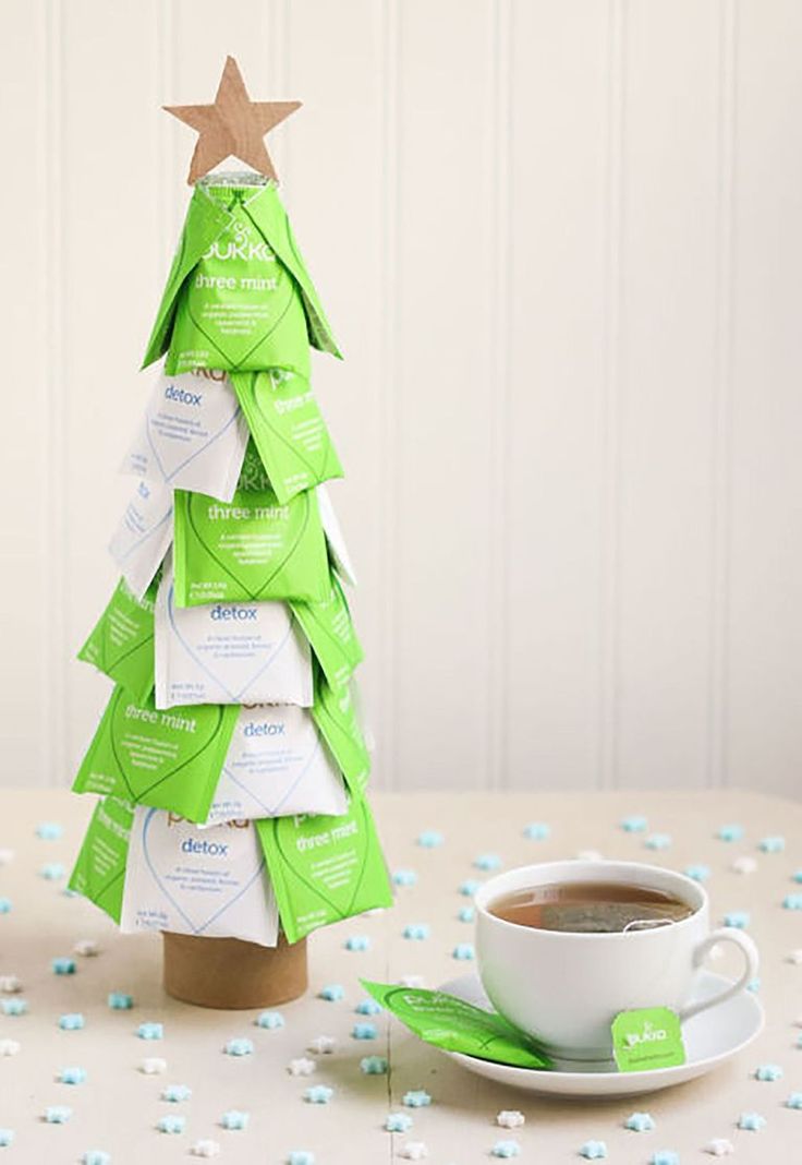 a cup of coffee sitting next to a christmas tree made out of tea bags and paper