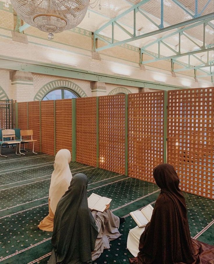 two women sitting on the floor in a room with wooden partitions and green carpet