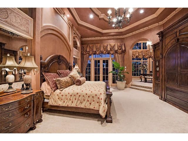 a bedroom with a bed, dressers and chandelier in the middle of it