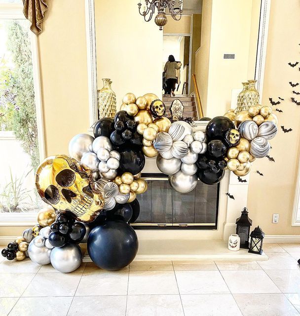 a fireplace decorated with black, silver and gold balloons in the shape of a skull