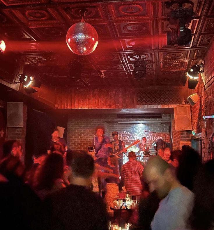 a group of people standing around in a room with red lights and disco balls hanging from the ceiling