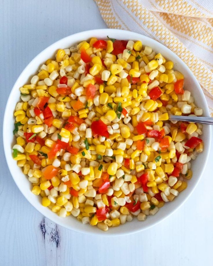 a white bowl filled with corn on top of a table