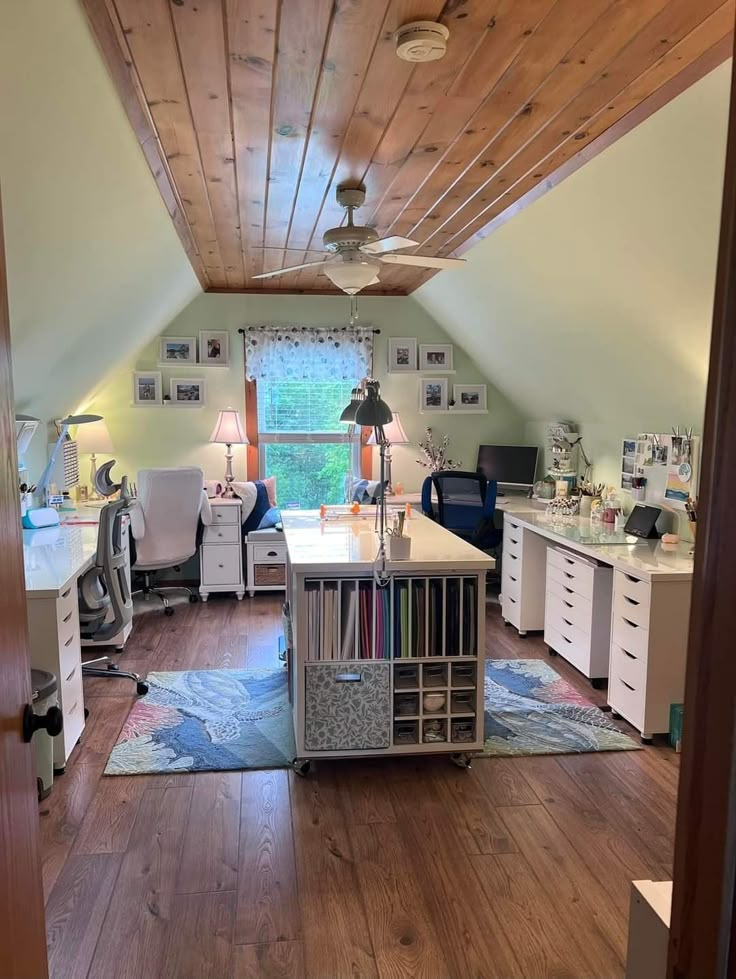 an office with wood floors and white desks in the middle of a large room