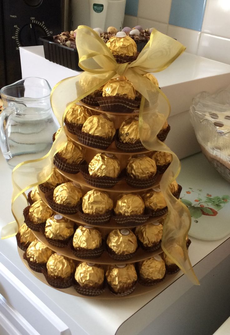 a cake made out of chocolates and wrapped in yellow ribbon on top of a counter