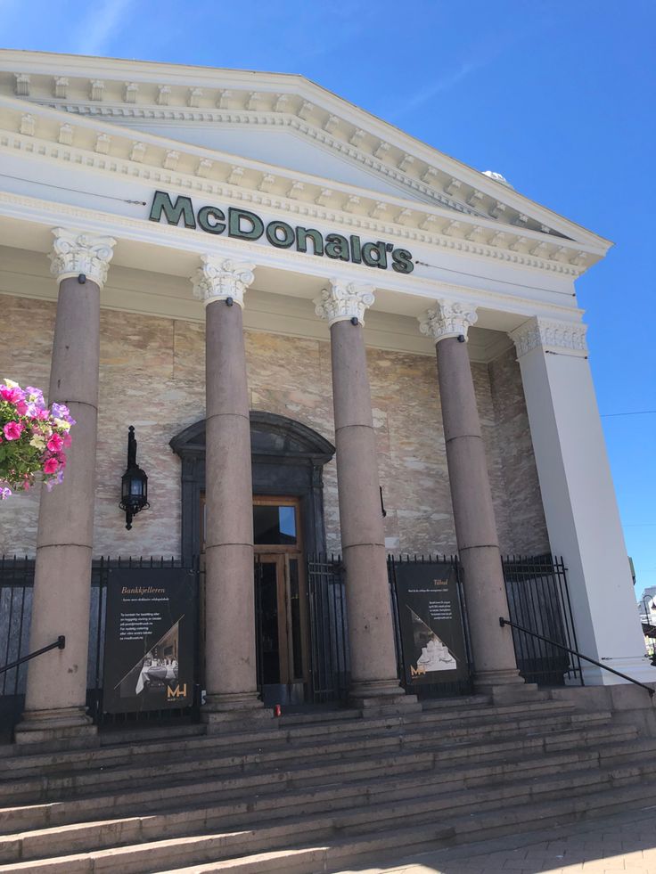 the front entrance to mcdonald's restaurant with large columns and flowers hanging from it