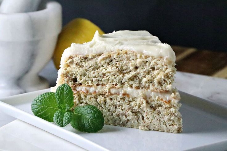 a piece of cake on a plate with a lemon and mint leaf next to it