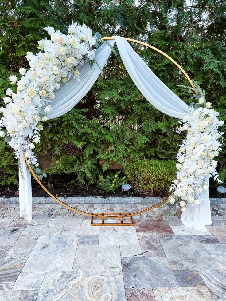 a wedding arch decorated with white flowers and greenery