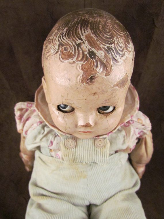 an old doll with blue eyes and white pants