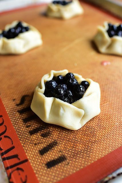 small pastries with blueberries are sitting on a baking sheet