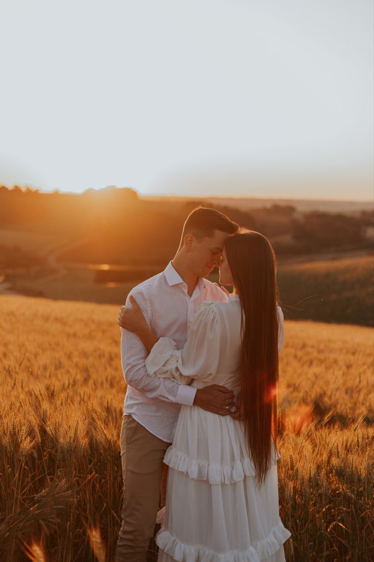 a man and woman standing in a field at sunset